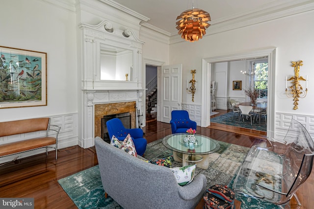 interior space with dark wood-type flooring, crown molding, an inviting chandelier, and a premium fireplace