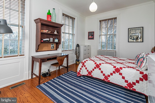 bedroom featuring multiple windows, crown molding, and dark wood-type flooring