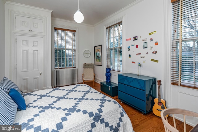 bedroom with crown molding, radiator, and dark hardwood / wood-style flooring