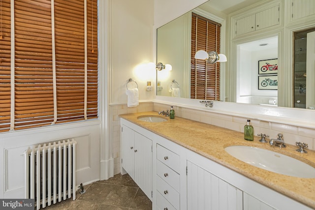 bathroom with tile flooring, radiator heating unit, and dual vanity