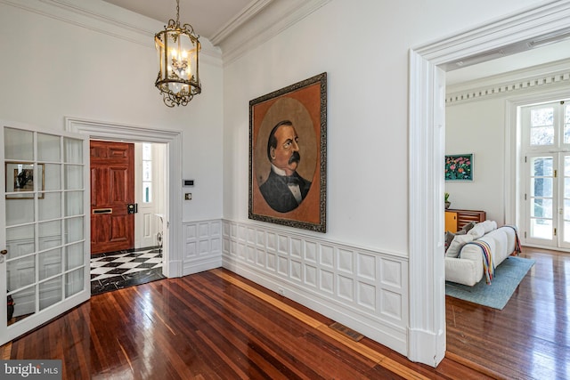 foyer entrance with an inviting chandelier, crown molding, and dark hardwood / wood-style floors