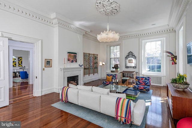 living room featuring ornamental molding, a high end fireplace, dark wood-type flooring, and a notable chandelier