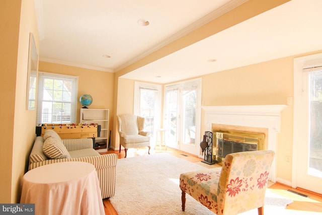 sitting room with ornamental molding and light hardwood / wood-style flooring