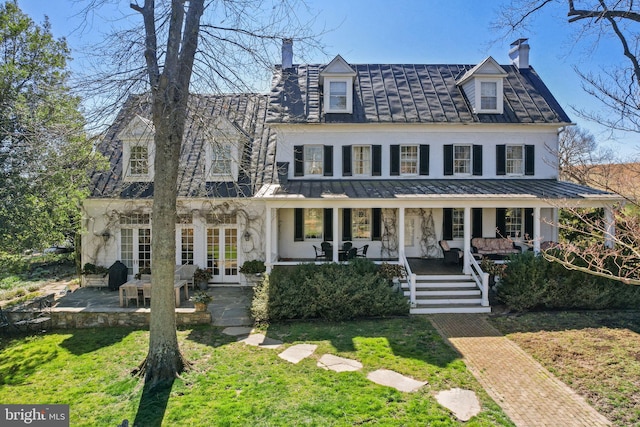 view of front of house with a porch, a front yard, and french doors