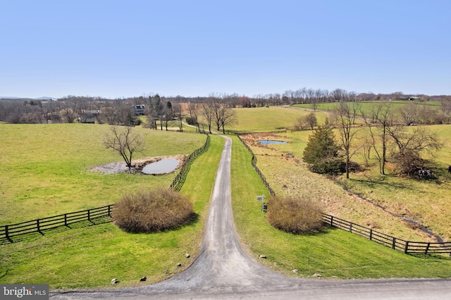 view of property's community with a rural view and a lawn