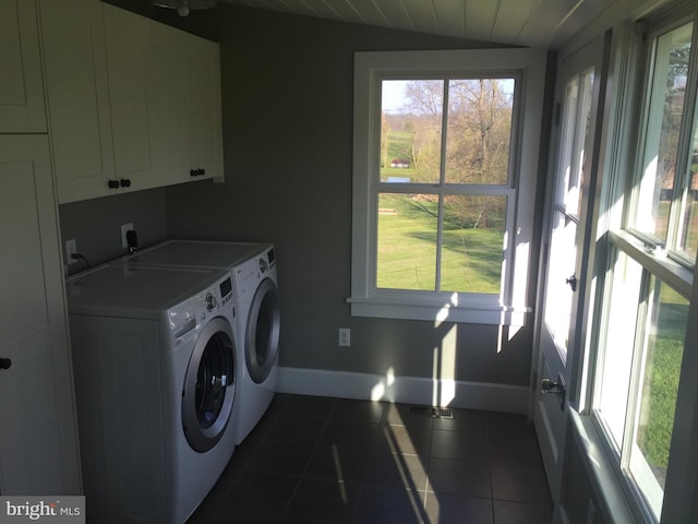 clothes washing area featuring cabinets, dark tile patterned flooring, and washer and dryer