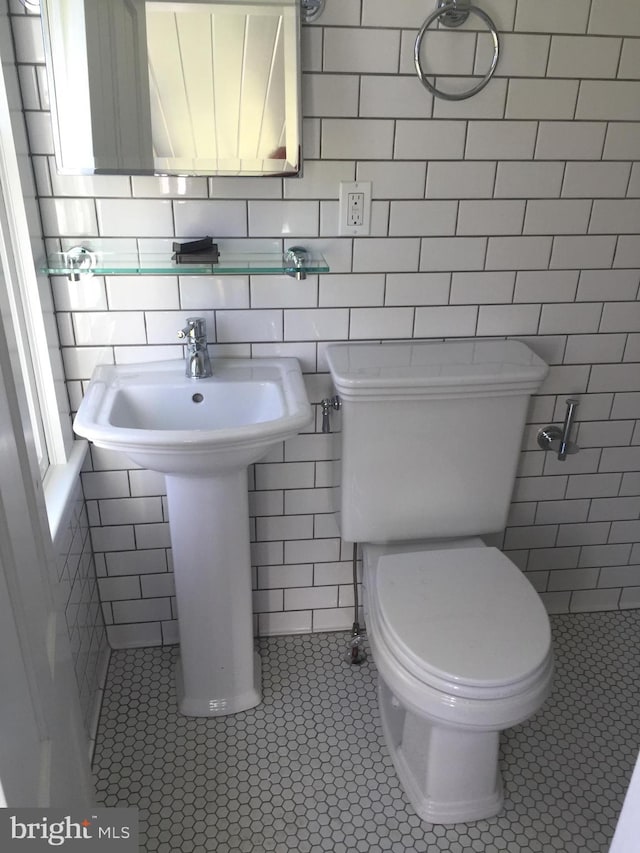 bathroom with sink, tile patterned flooring, tile walls, and toilet