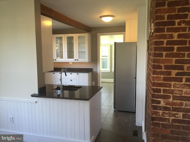 kitchen with white cabinets, sink, stainless steel fridge, dark tile patterned floors, and kitchen peninsula