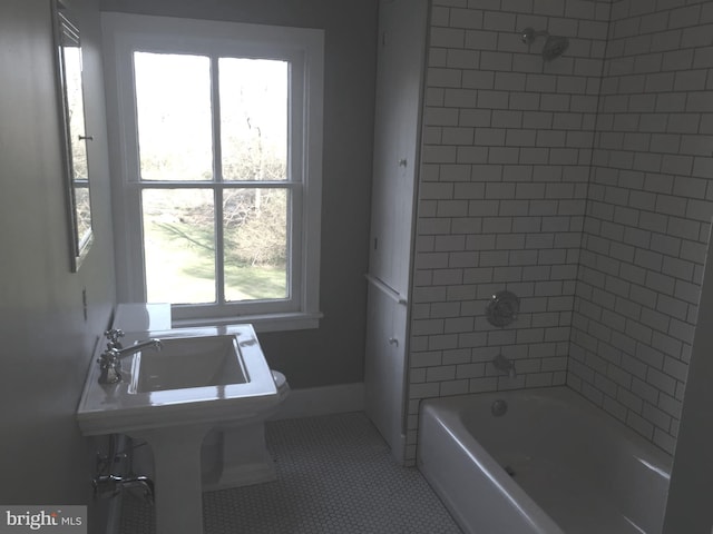 bathroom featuring tile patterned flooring, tiled shower / bath combo, and toilet