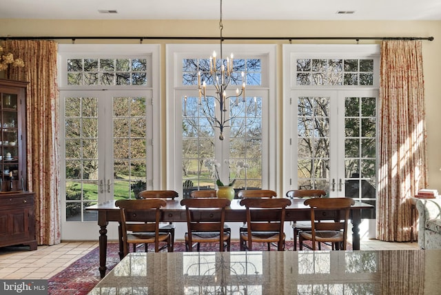 tiled dining space featuring a chandelier and french doors