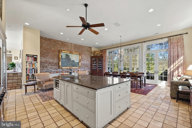 kitchen featuring pendant lighting, dark stone counters, french doors, white cabinets, and brick wall