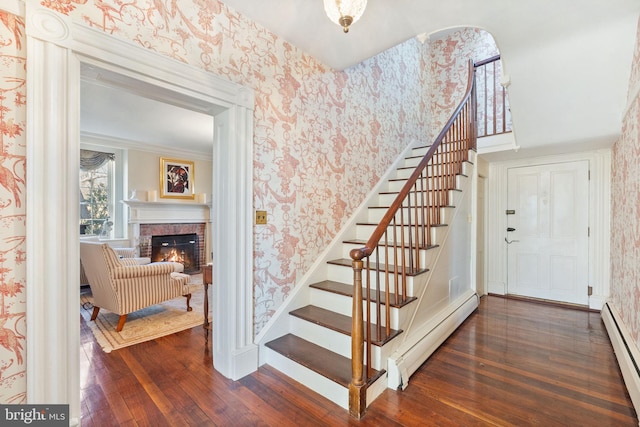 stairs featuring a fireplace, hardwood / wood-style floors, and a baseboard heating unit