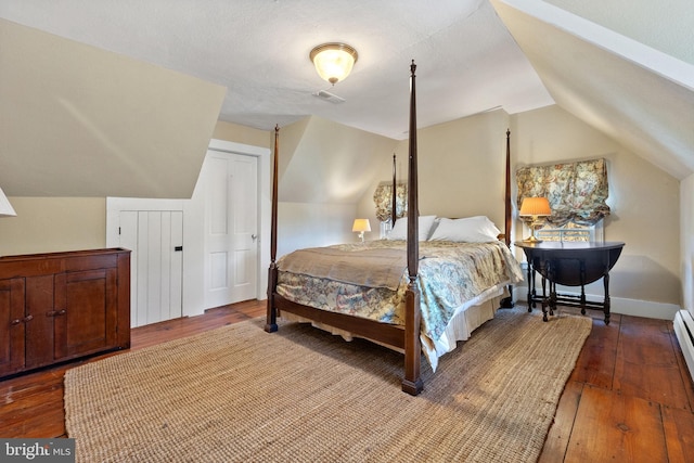 bedroom featuring baseboard heating, hardwood / wood-style floors, and lofted ceiling