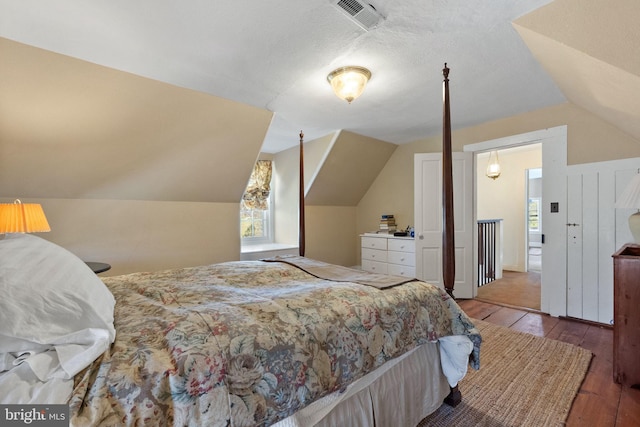 bedroom with hardwood / wood-style floors and lofted ceiling