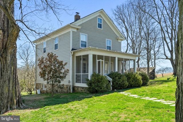 view of home's exterior featuring a sunroom and a lawn