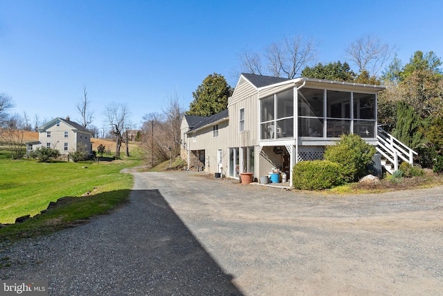 view of side of home featuring a sunroom and a yard