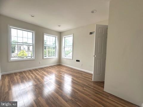 spare room featuring baseboards and wood finished floors