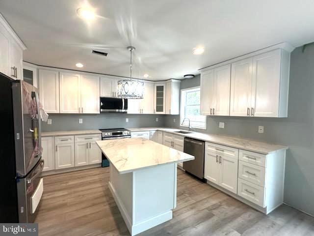 kitchen with appliances with stainless steel finishes, white cabinetry, and a sink