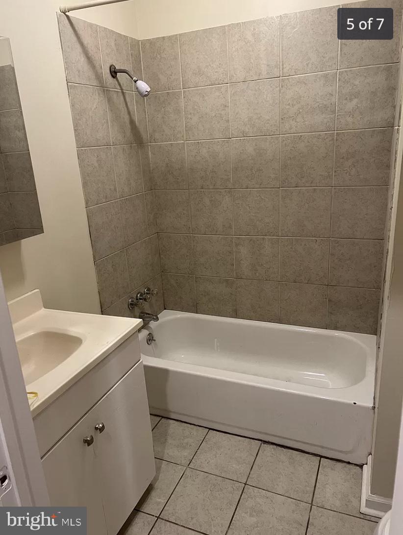 bathroom featuring tile flooring, oversized vanity, and tiled shower / bath