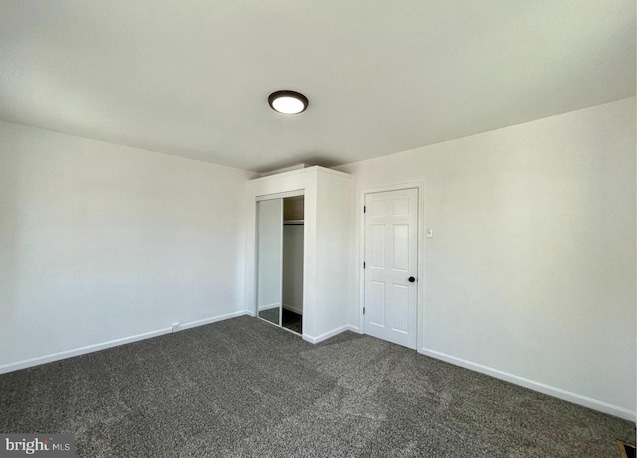 unfurnished bedroom with a closet and dark carpet