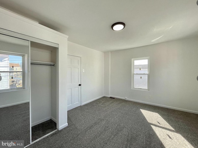 unfurnished bedroom with a closet and dark carpet