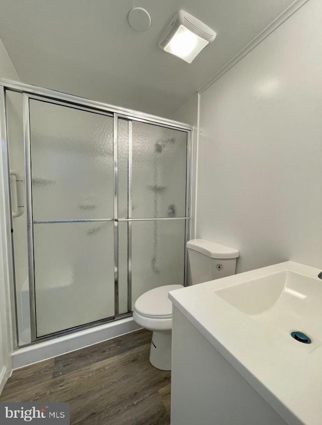 bathroom with vanity, a shower with door, crown molding, hardwood / wood-style flooring, and toilet