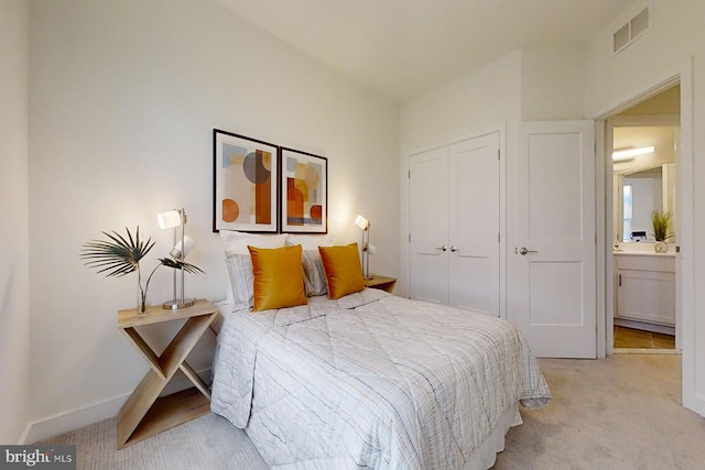 bedroom featuring light carpet, a closet, and ensuite bathroom