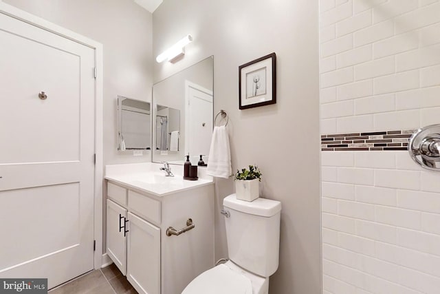 bathroom with tile flooring, vanity with extensive cabinet space, and toilet