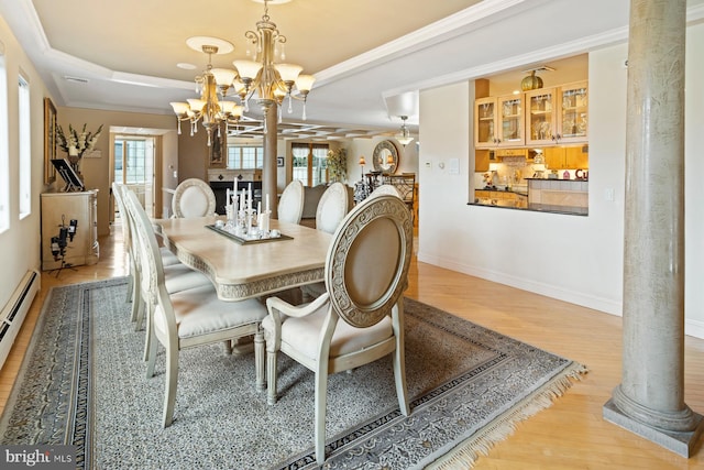 dining space featuring an inviting chandelier, light hardwood / wood-style floors, crown molding, decorative columns, and a raised ceiling