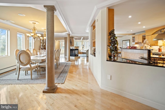 interior space featuring decorative columns, ornamental molding, a chandelier, and light hardwood / wood-style floors