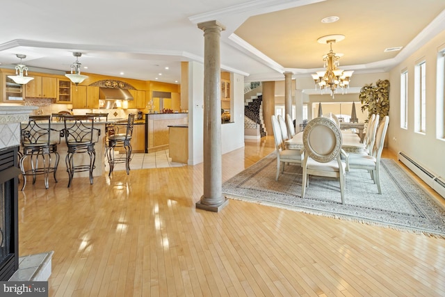 dining area featuring crown molding, light hardwood / wood-style floors, decorative columns, and a chandelier