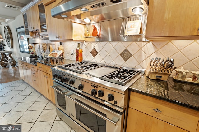 kitchen featuring light tile floors, dark stone counters, double oven range, ventilation hood, and tasteful backsplash