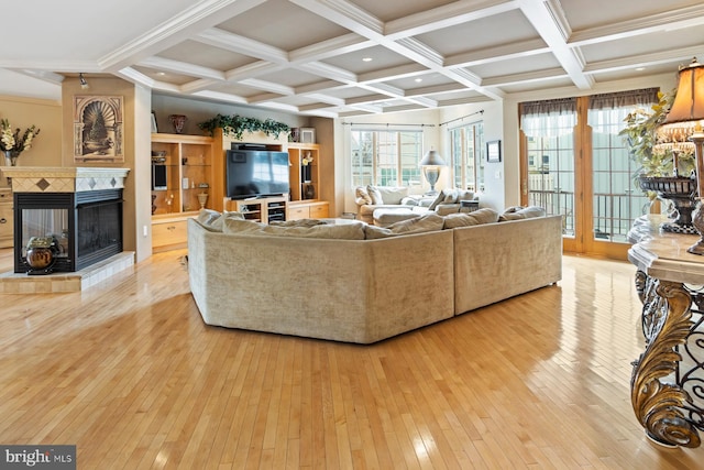 living room featuring a tiled fireplace, coffered ceiling, beamed ceiling, and light wood-type flooring