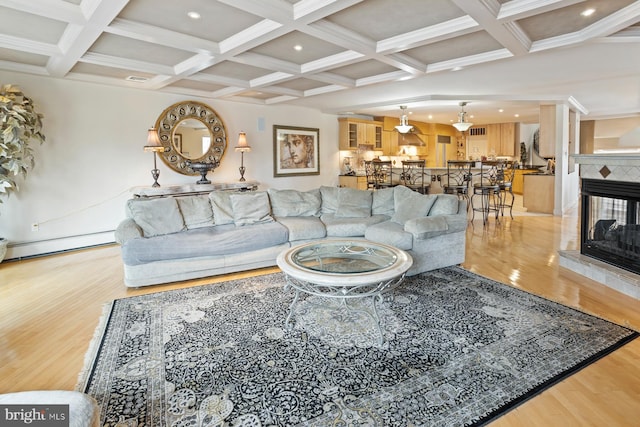 living room featuring a tiled fireplace, beam ceiling, light hardwood / wood-style flooring, and coffered ceiling