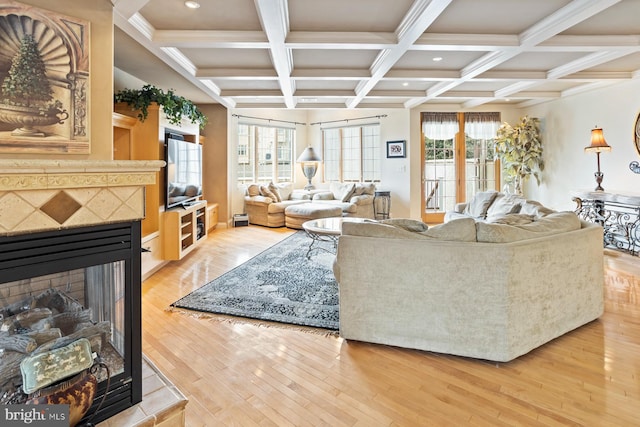 living room featuring coffered ceiling, a tile fireplace, light hardwood / wood-style flooring, and beamed ceiling