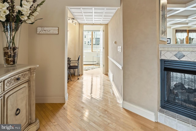 corridor featuring coffered ceiling, light hardwood / wood-style floors, and beamed ceiling