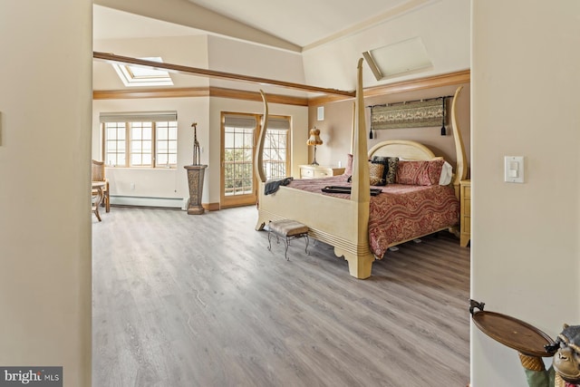 bedroom with vaulted ceiling with skylight, light hardwood / wood-style flooring, and a baseboard heating unit