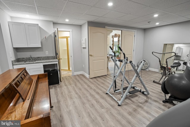 workout room with light hardwood / wood-style flooring, sink, and a paneled ceiling