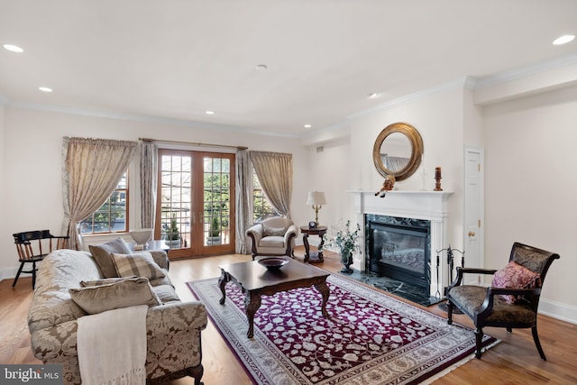 living room with a high end fireplace, light hardwood / wood-style floors, french doors, and crown molding