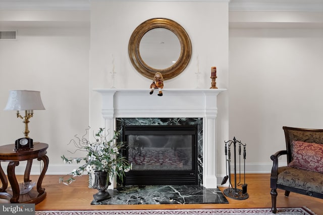 interior details with a premium fireplace, hardwood / wood-style floors, and ornamental molding