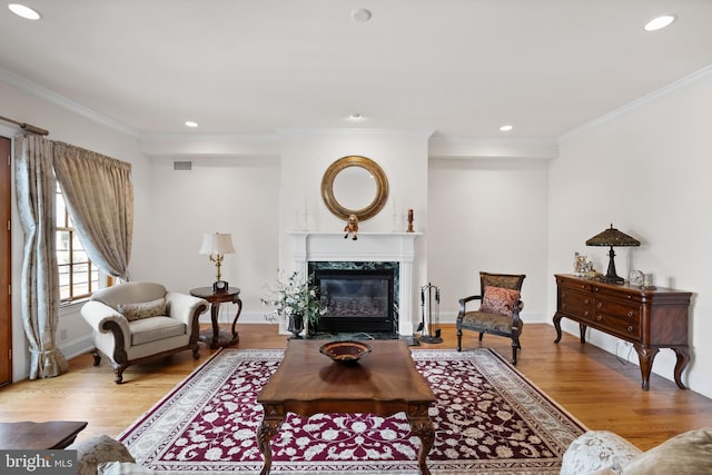 living room featuring ornamental molding, light hardwood / wood-style flooring, and a fireplace