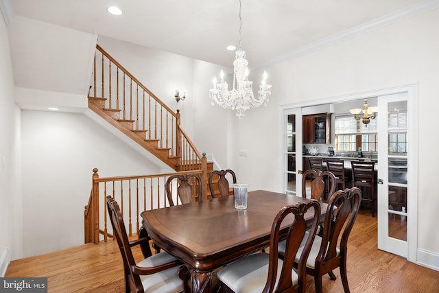 dining room with a chandelier, crown molding, and light hardwood / wood-style flooring