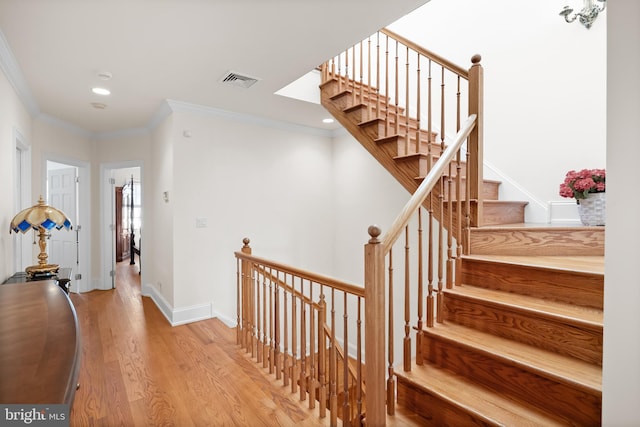 stairway with crown molding and light wood-type flooring