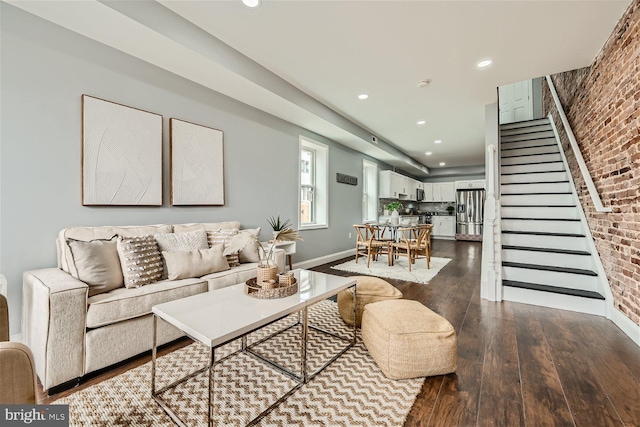 living room with brick wall and dark wood-type flooring