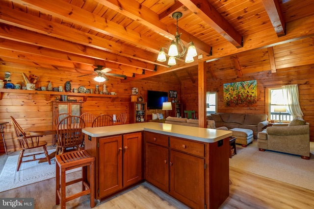 kitchen featuring wooden walls, light hardwood / wood-style flooring, and decorative light fixtures