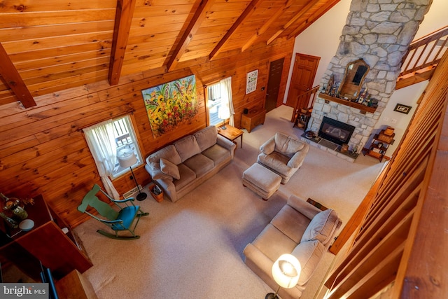 carpeted living room with high vaulted ceiling, wooden walls, a fireplace, beam ceiling, and wood ceiling