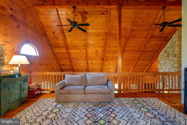 living room featuring lofted ceiling with beams, light wood-type flooring, wooden walls, and wooden ceiling