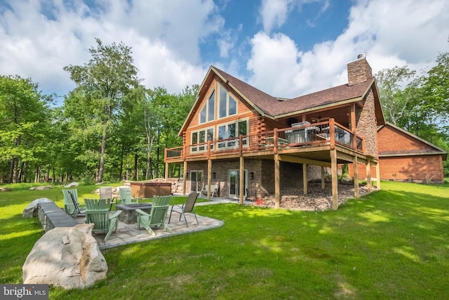 rear view of house with a fire pit, a deck, a lawn, and a patio area