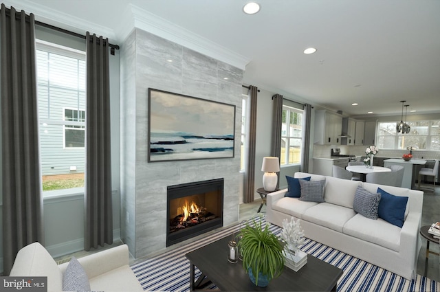 living area with ornamental molding, a fireplace, a wealth of natural light, and recessed lighting