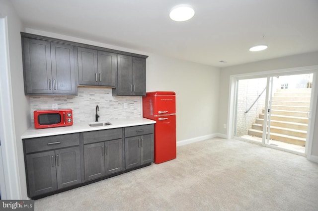 kitchen featuring backsplash, light carpet, and sink